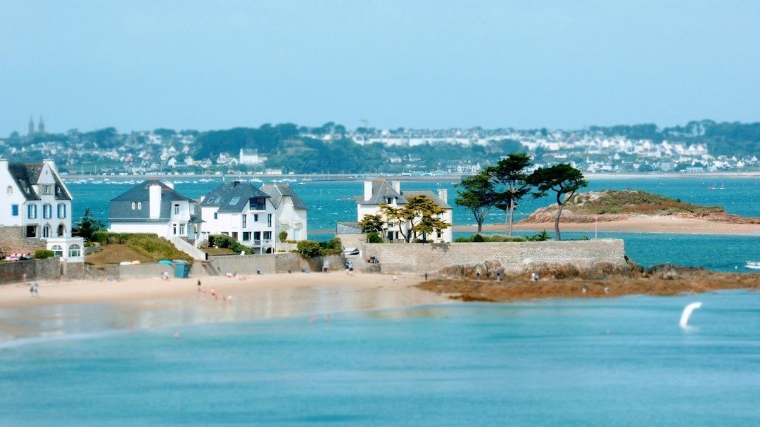 Vue côtière de maisons face à une baie et un îlot rocheux
