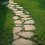 Chemin de dalles traversant une pelouse, évoquant un droit de passage